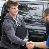 Volunteer shaking hands with arriving student